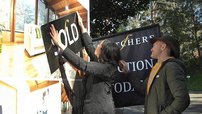 A "sold" sticker is put on a home's "for sale" sign