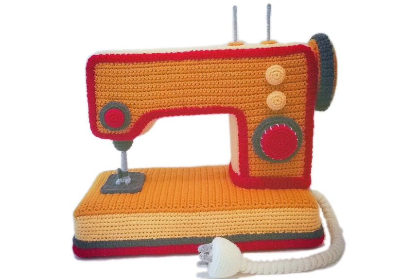 A bright orange crocheted sewing machine