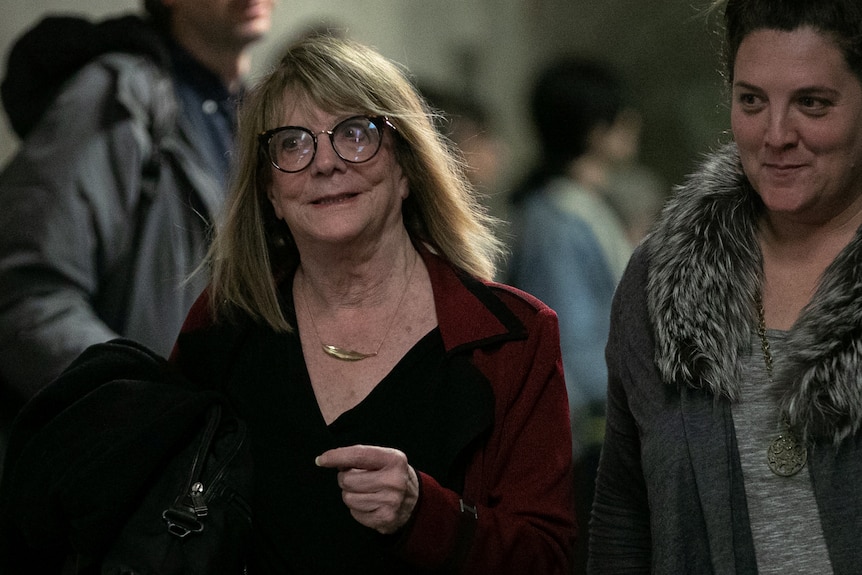 A woman in glasses walking in a hurry gives a soft smile