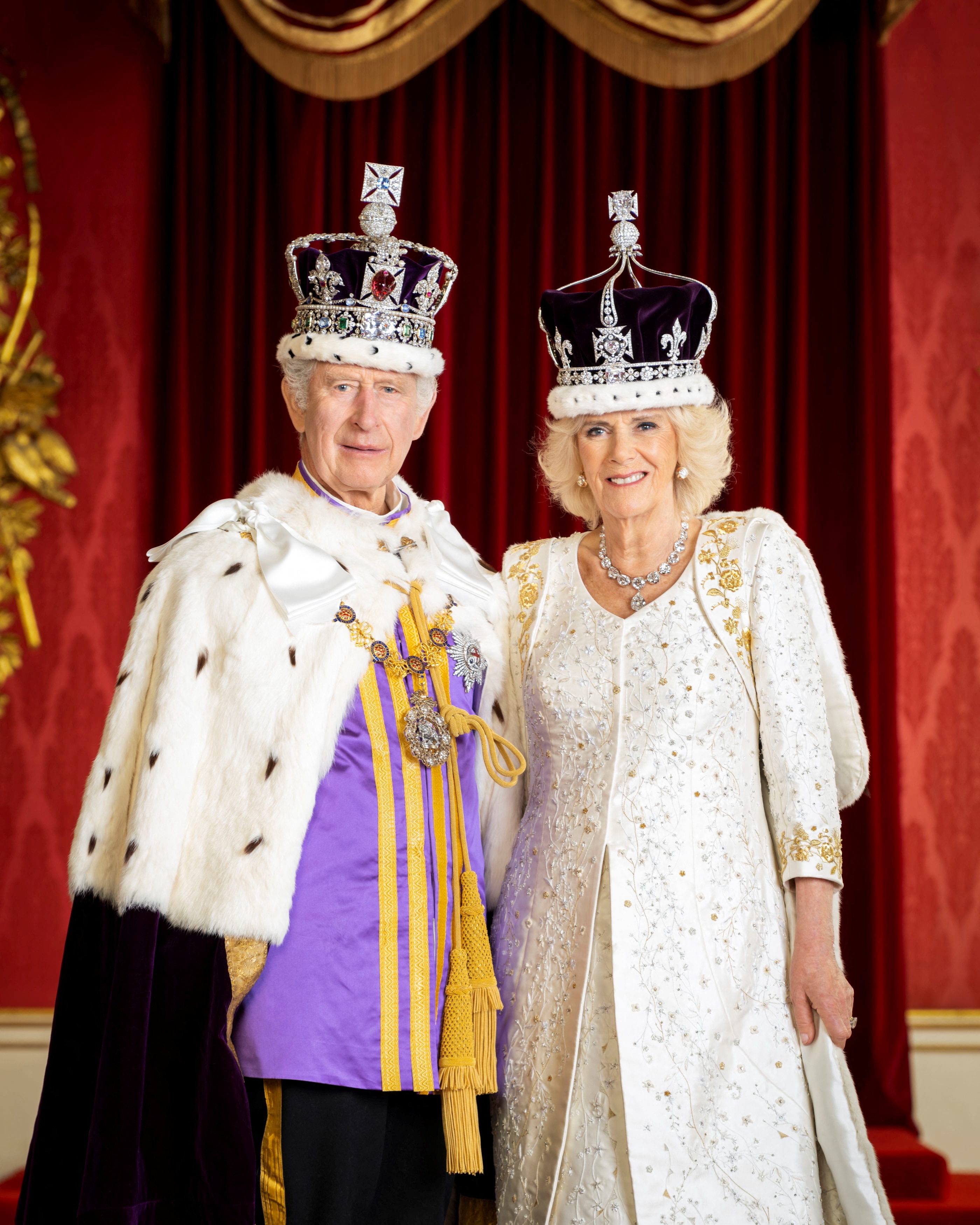 Charles and Camilla smile in their crowns and regalia.