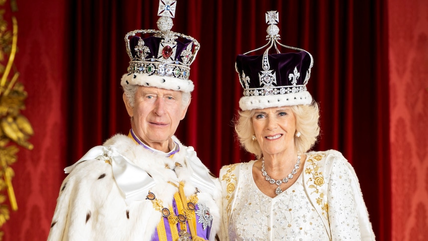 Charles and Camilla smile in their crowns and regalia.