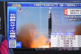 A passerby looks at a television screen showing a news report about North Korea.