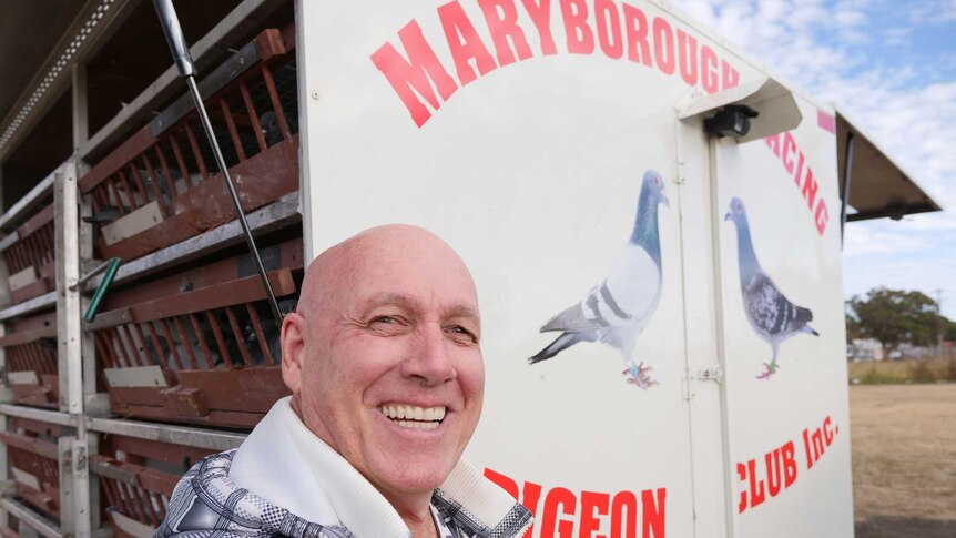 George Simpson stands beside Maryborough Racing Pigeon Club trailer containing hundreds of racing pigeons.