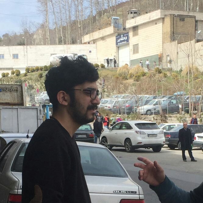 Mehdi Rajabian stands outside Evin Prison as traffic drives by.