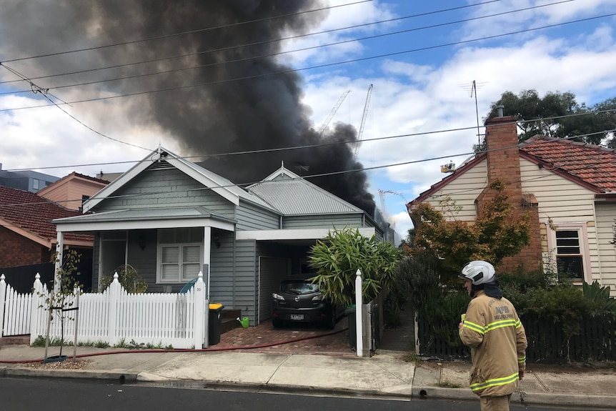 A black smoke plume rising behind a house