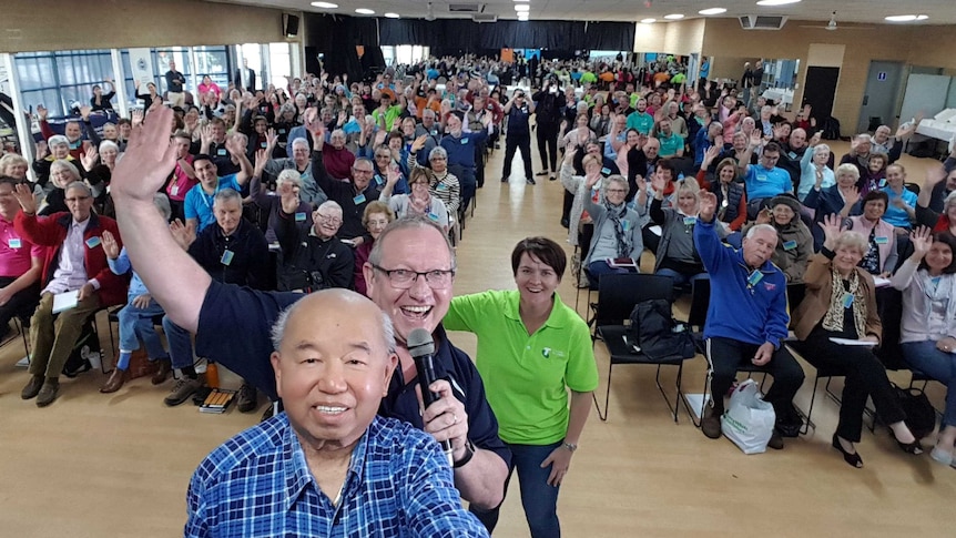 A room full of seniors with Michael Tan taking selfie in the foreground