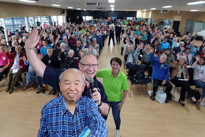 A room full of seniors with Michael Tan taking selfie in the foreground