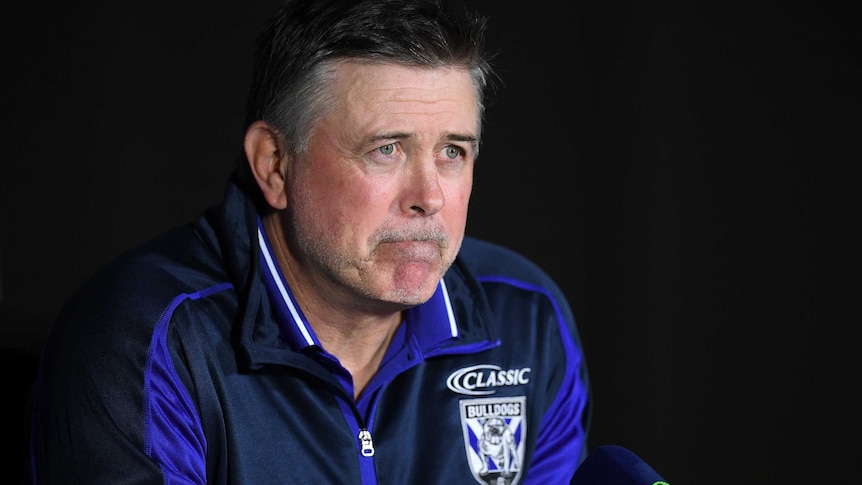 Dean Pay speaks to the media in front of a black background