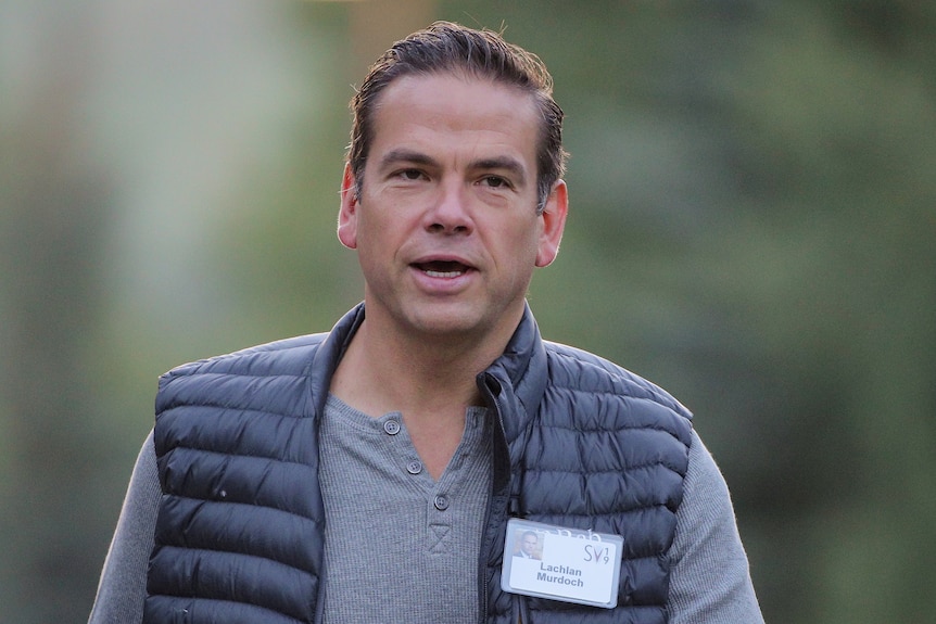 Lachlan Murdoch  walks towards the camera wearing a grey henley and a puffer vest.