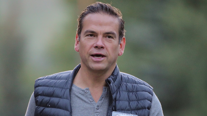 Lachlan Murdoch  walks towards the camera wearing a grey henley and a puffer vest.