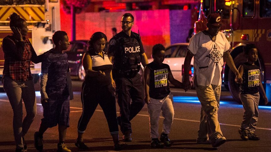 Police escort civilians away from the scene of a shooting.