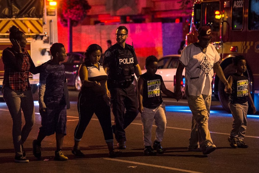 Police escort civilians away from the scene of a shooting.