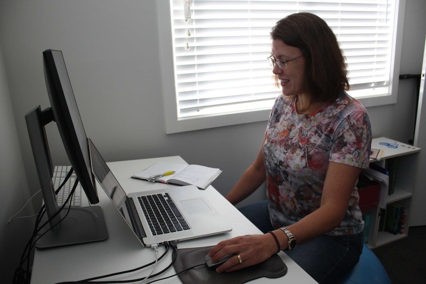 Megan smiles while sitting at her computer.