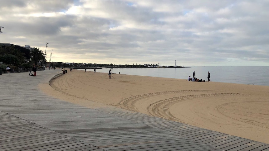 A clean beach in St Kilda, Melbourne with a wide sky littered with clouds.