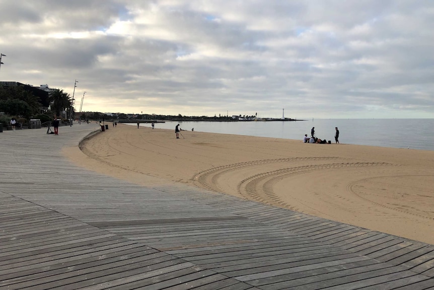 A clean beach in St Kilda, Melbourne with a wide sky littered with clouds.