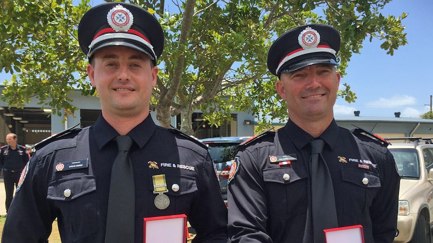 Two firefighters in formal uniform with medals.