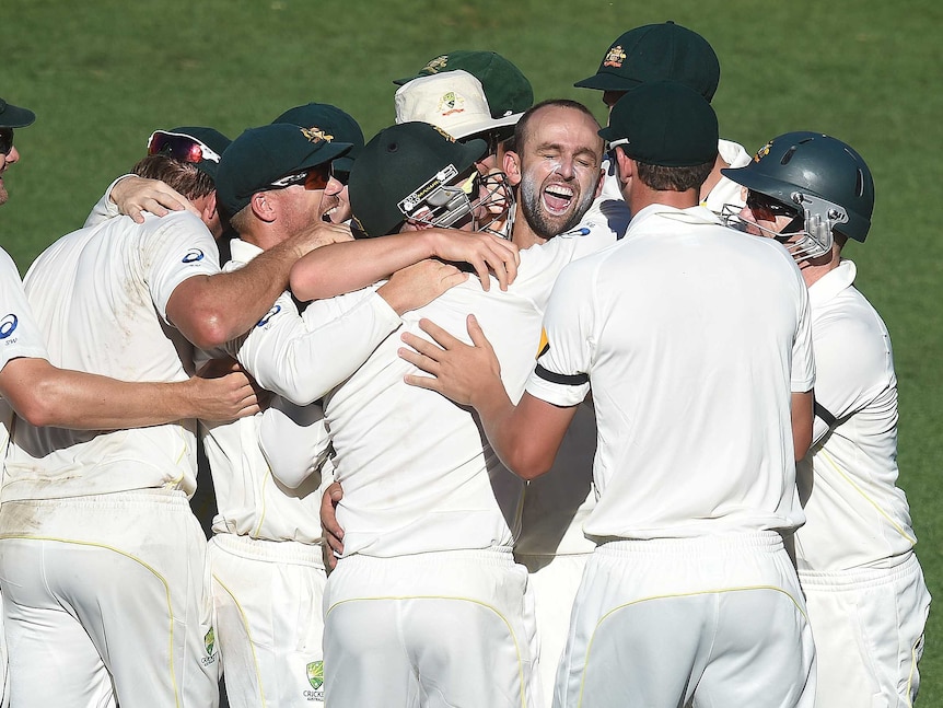 The Australian cricket team react with bowler Nathan Lyon (centre) after he took the last wicket to give Australia victory on day 5 of the first Test match between Australia and India at the Adelaide Oval