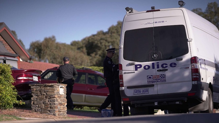 Police officers and a van in a suburban street.