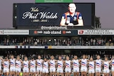 Emotional moment ... The Crows line up for a minute's silence to pay respect to the late Phil Walsh