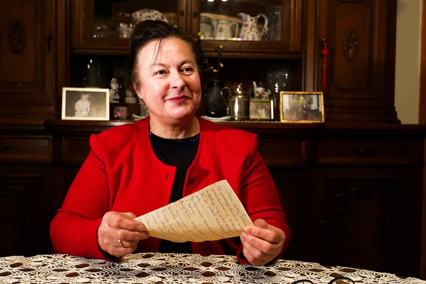 A woman holds an old letter.