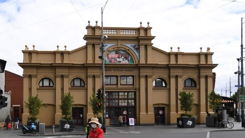 People wearing masks cross the street in front of the Queen Victoria Market in Melbourne.