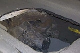 A sinkhole 1mx1mx1m on a concrete road.