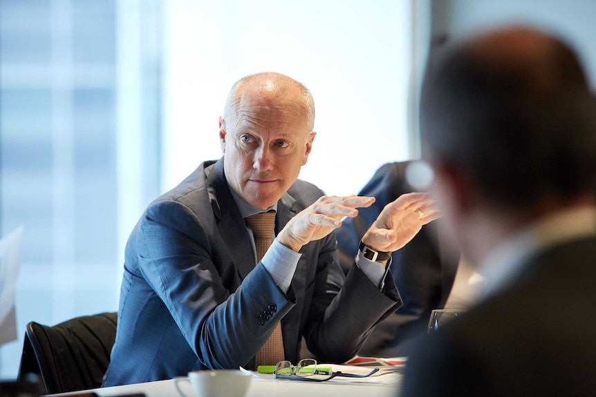 James Fazzino, sitting at a table, gestures as he talks.