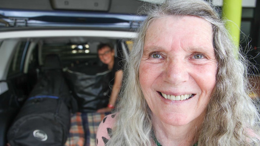 70 year old woman with grey hair smiles at the camera