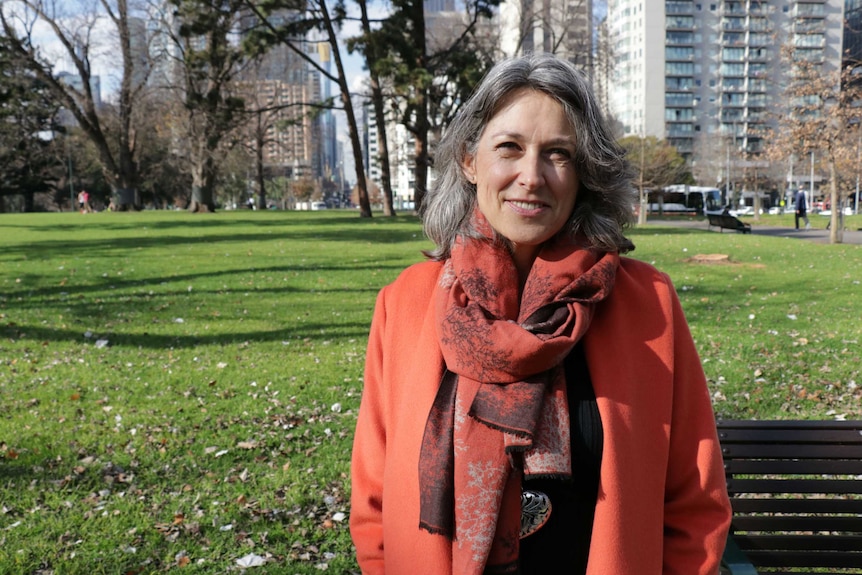 Naomi Halpern sits on bench in Melbourne's Exhibition Gardens, she experienced a financial crisis which she is still paying off.