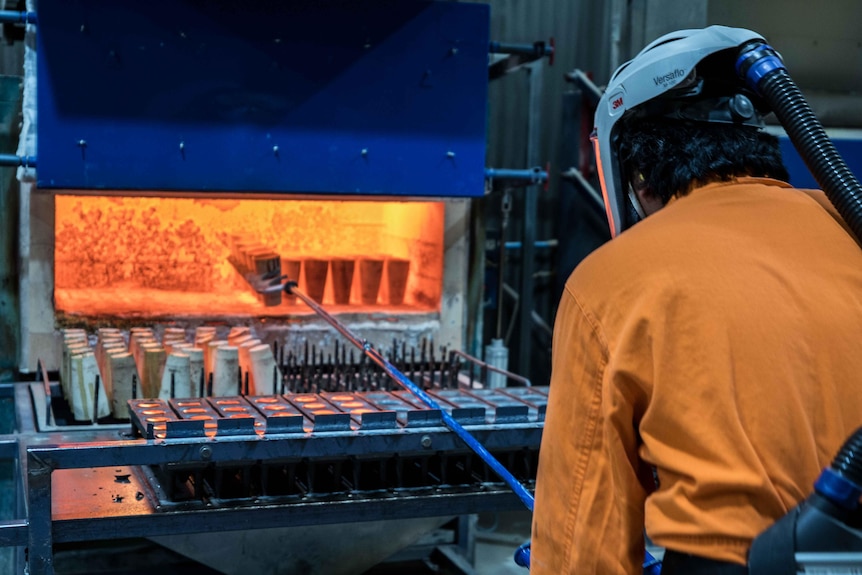 A worker next to a hot furnace. 