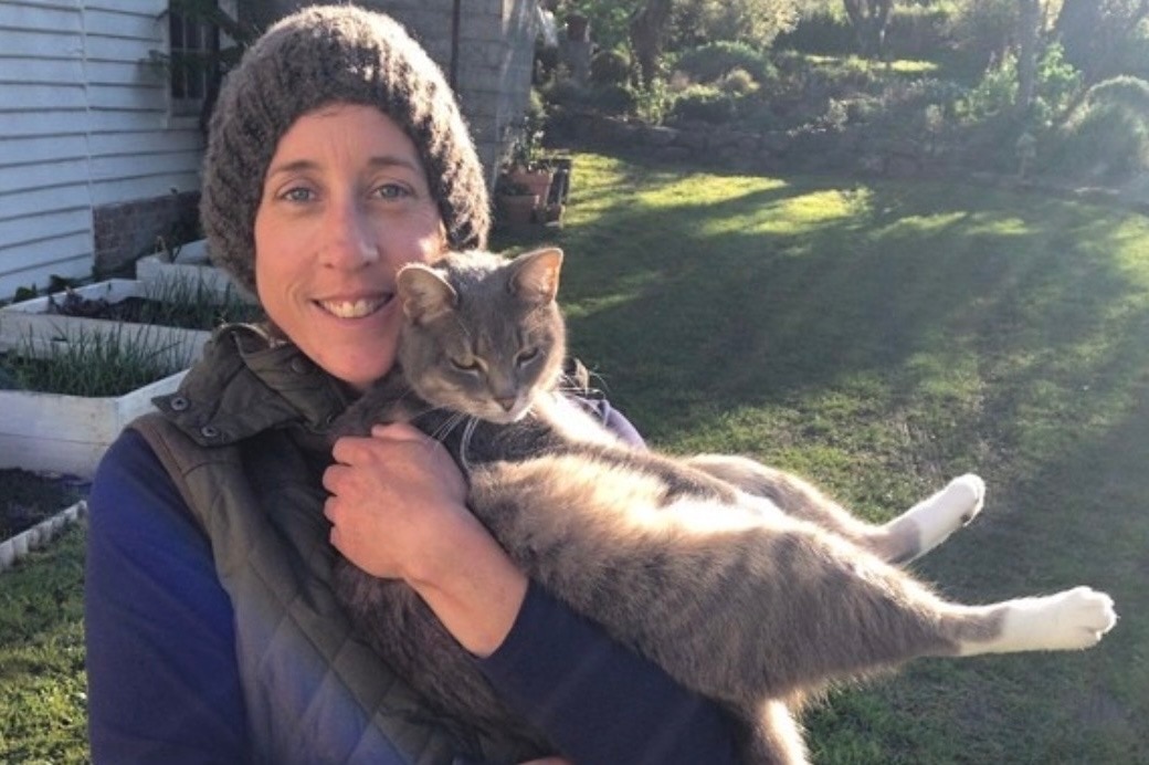 Nicky Stewart, smiling, holds her cat while outside.
