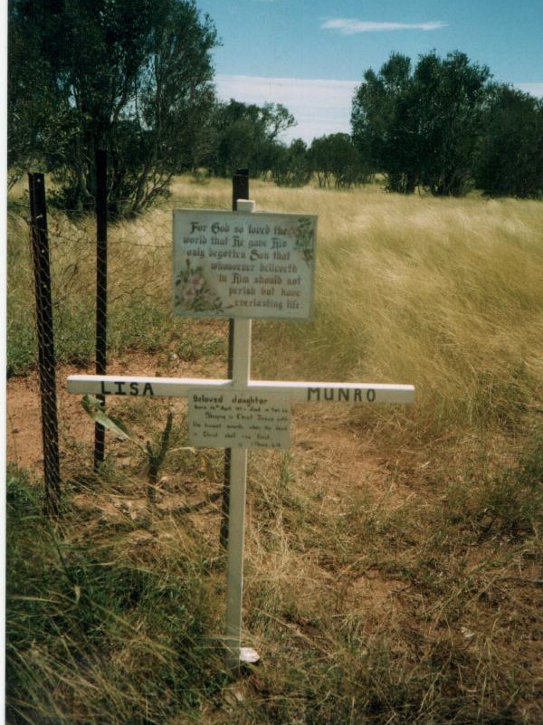A cross with Lisa Munro written on it, a religious sign and a small tree