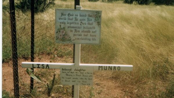 A cross with Lisa Munro written on it, a religious sign and a small tree
