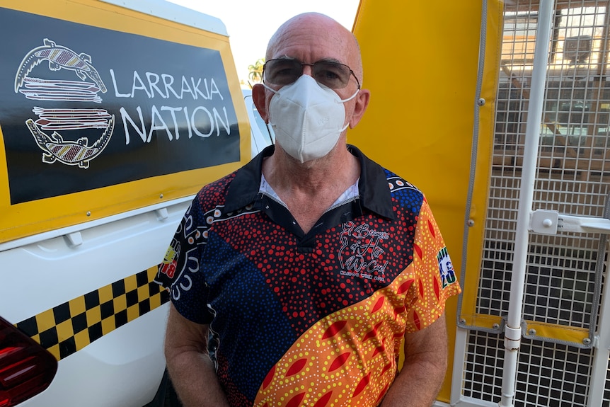 Larrakia Nation chief executive Robert Cooper standing in front of a patrol vehicle.