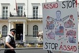 A police officer patrolling outside the Syrian embassy walks past a placard left by protesters in London.