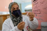 A Palestinian health worker prepares to give a member of education staff a dose of Sinopharm COVID-19 vaccine