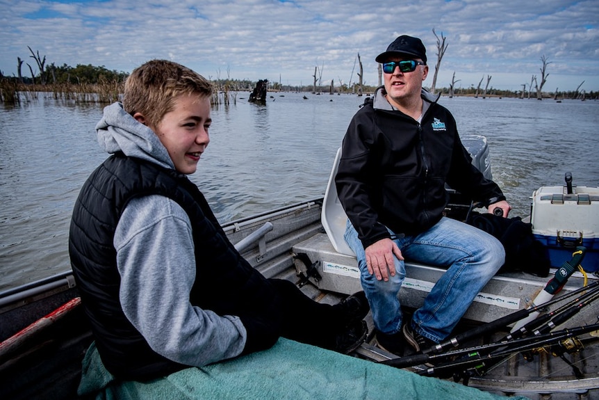 A man and his son fish from a tinny on the Murray River.