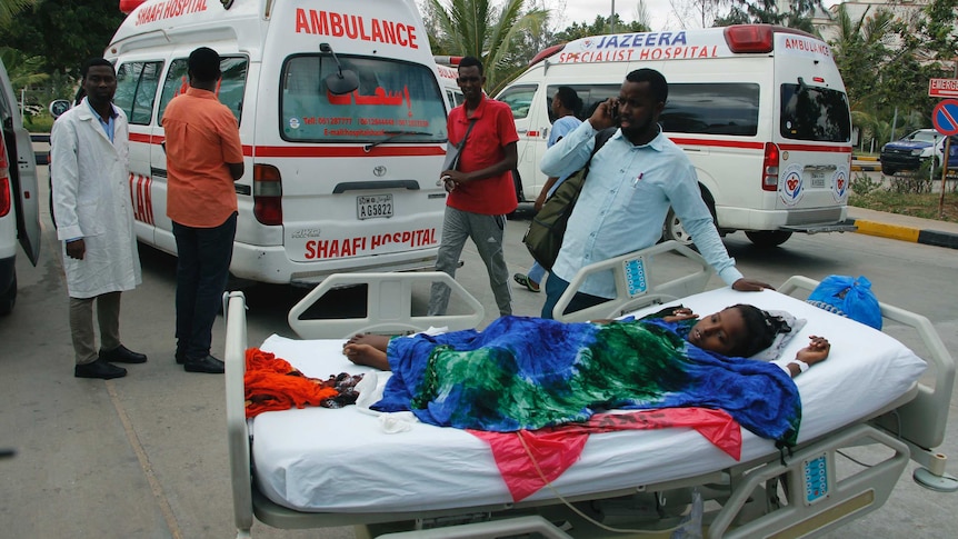 A child is wheeled on a medical bed by hospital staff.