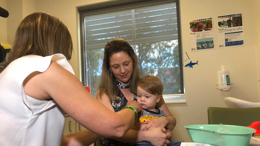 Canberra mum with young kid on lap who is getting flu shot