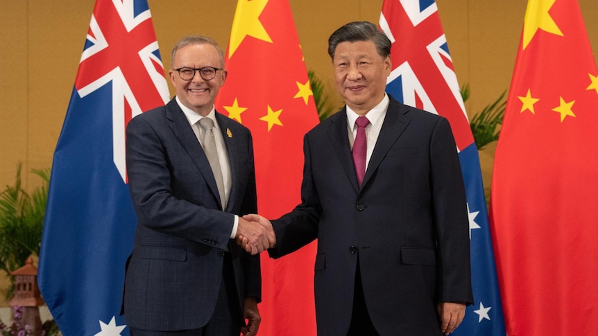 Anthony Albanese and Xi Jinping shaking hands with chinese and australian flags in the background