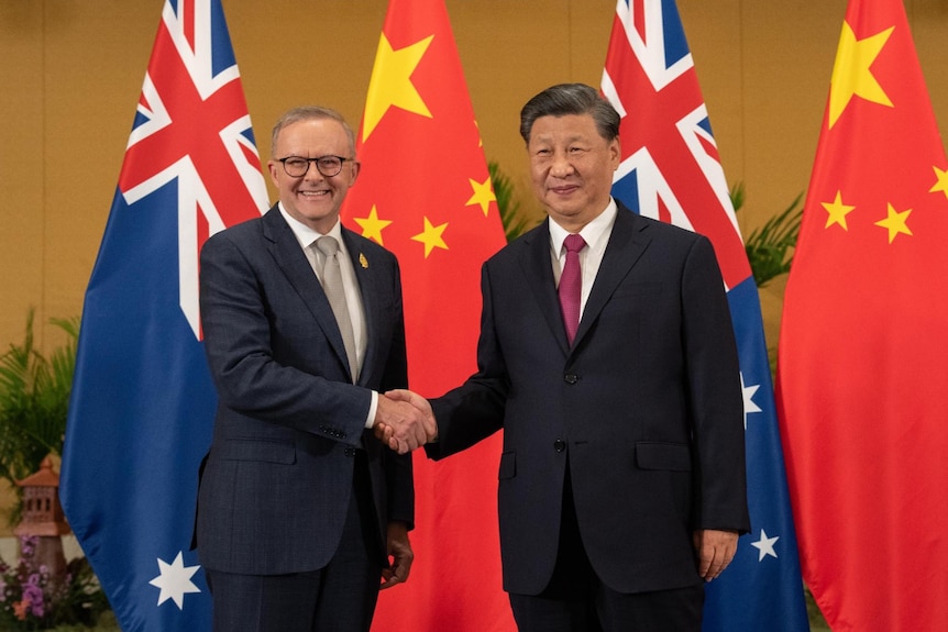 Anthony Albanese and Xi Jinping shaking hands with chinese and australian flags in the background