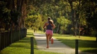 A woman runs along a track in a park.