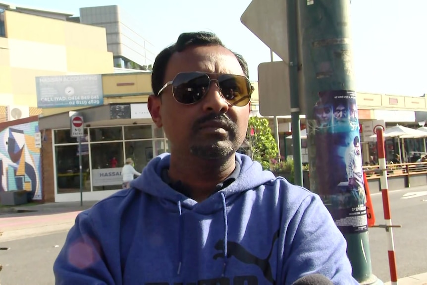 a man wearing dark glasses speaks to a reporter outside a school in liverpool