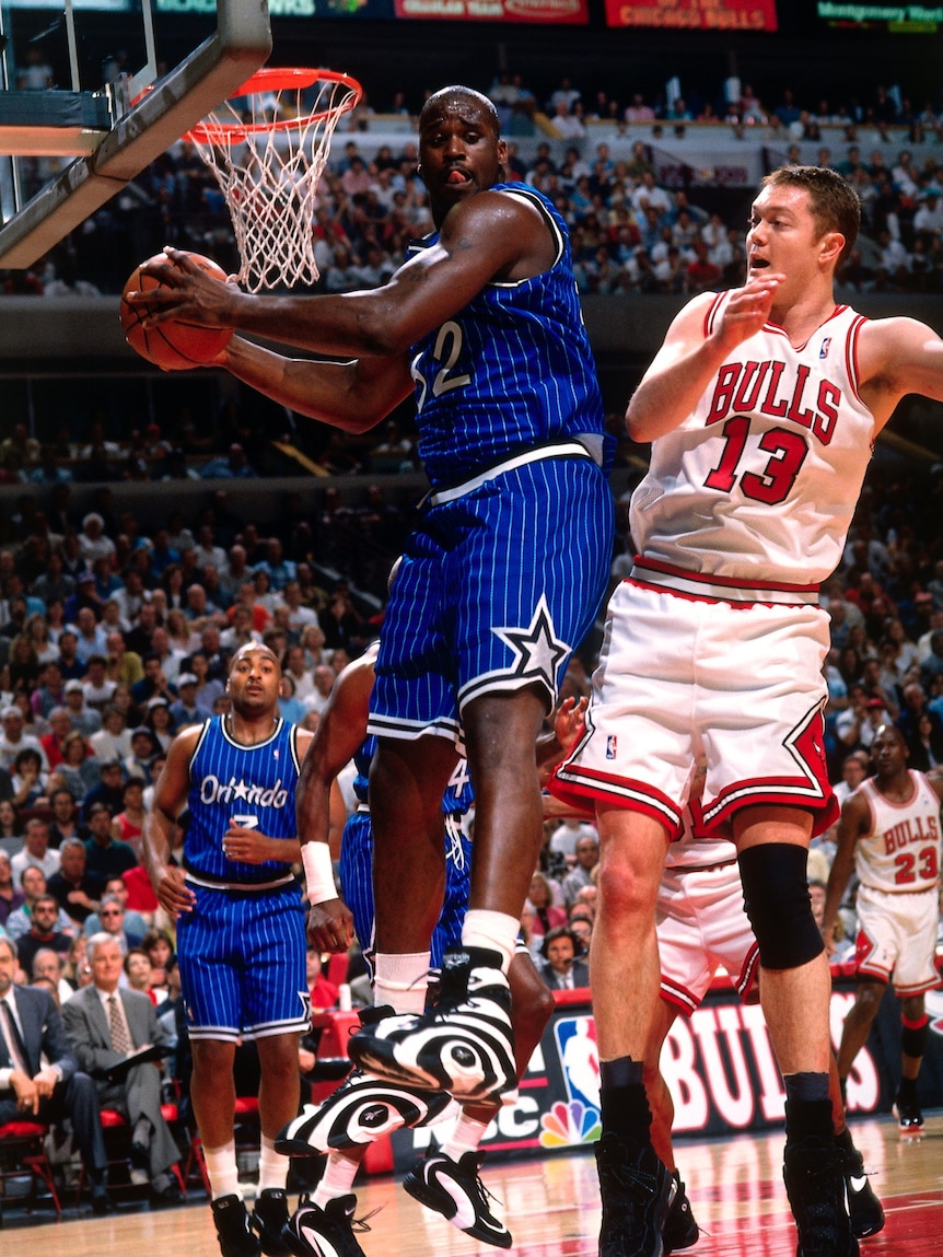 Luc Longley of the Chicago Bulls jumps in the air pushing on Shaquille O'Neal from Orlando Magic as they chase the ball