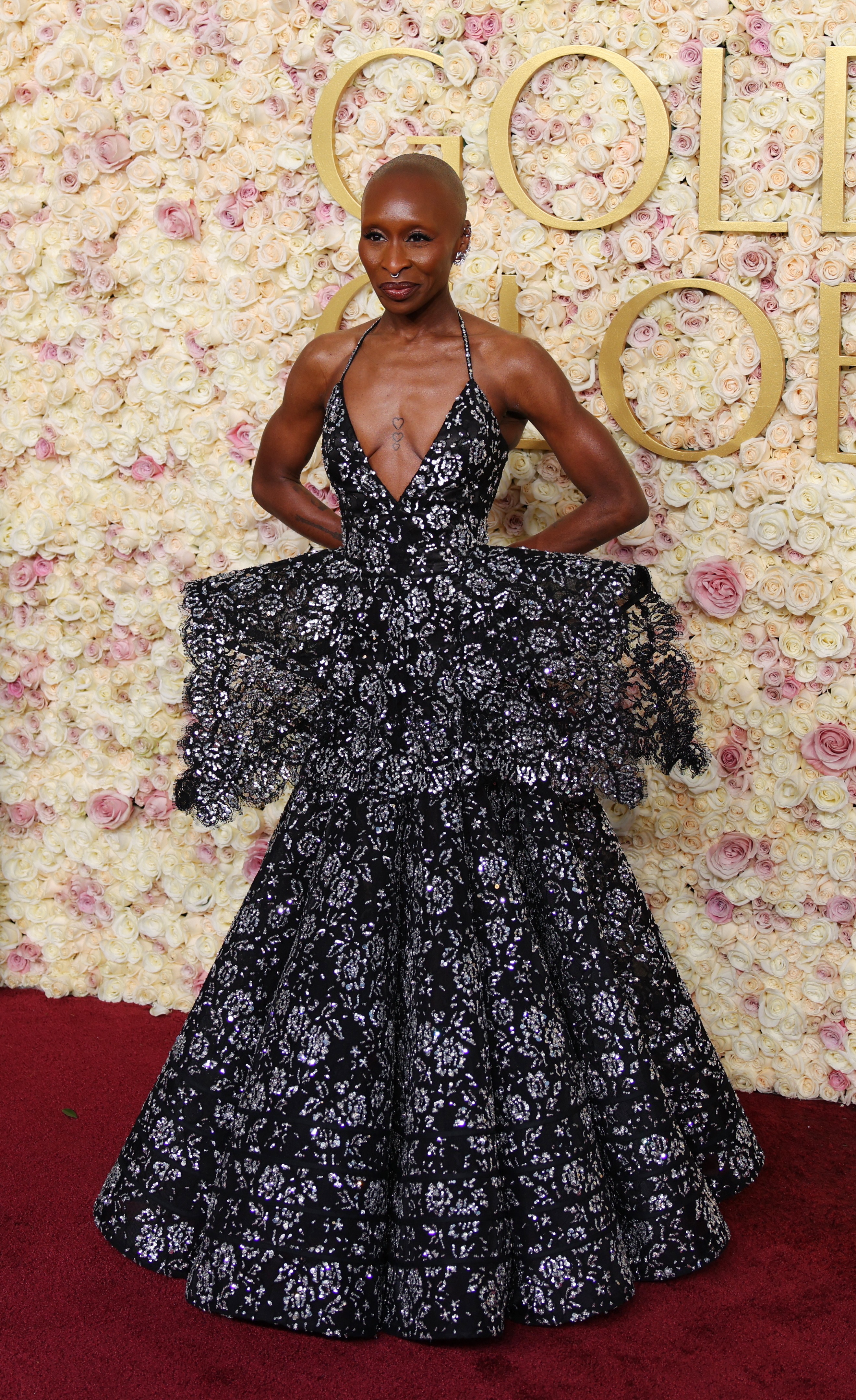 Cynthia Erivo wearing a black dress with white sparkles. The neckline is drops far down