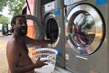 Aboriginal man smiling as he puts laundry into a washing machine
