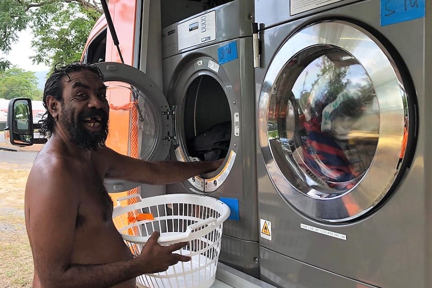 Aboriginal man smiling as he puts laundry into a washing machine