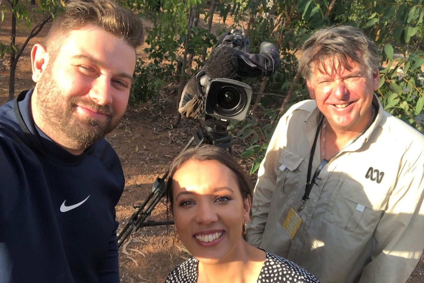 Three looking to camera with a camera on tripod in background.