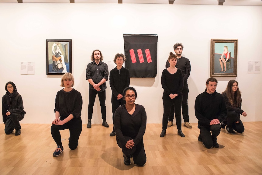 Protesters stand next to Picasso's Weeping Woman after covering it with a black cloth.