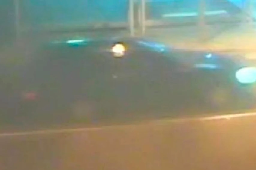A blurry CCTV still of a black car.